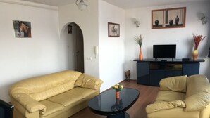 Un salon comprenant un canapé, deux fauteuils, une table basse et un téléviseur.