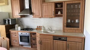 Une cuisine compacte avec des meubles en bois, une cuisinière encastrée, un four à micro-ondes, un évier et un lave-vaisselle.