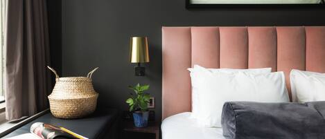 A neatly arranged hotel room with a bed, bedside table, lamp, and a wall-mounted picture.