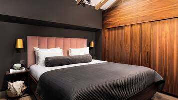 A modern bedroom with a large bed, dark walls, wooden paneling, and two bedside lamps.
