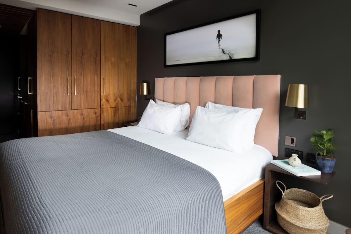 Quarto moderno com cama grande, guarda-roupa de madeira e quadro na parede.