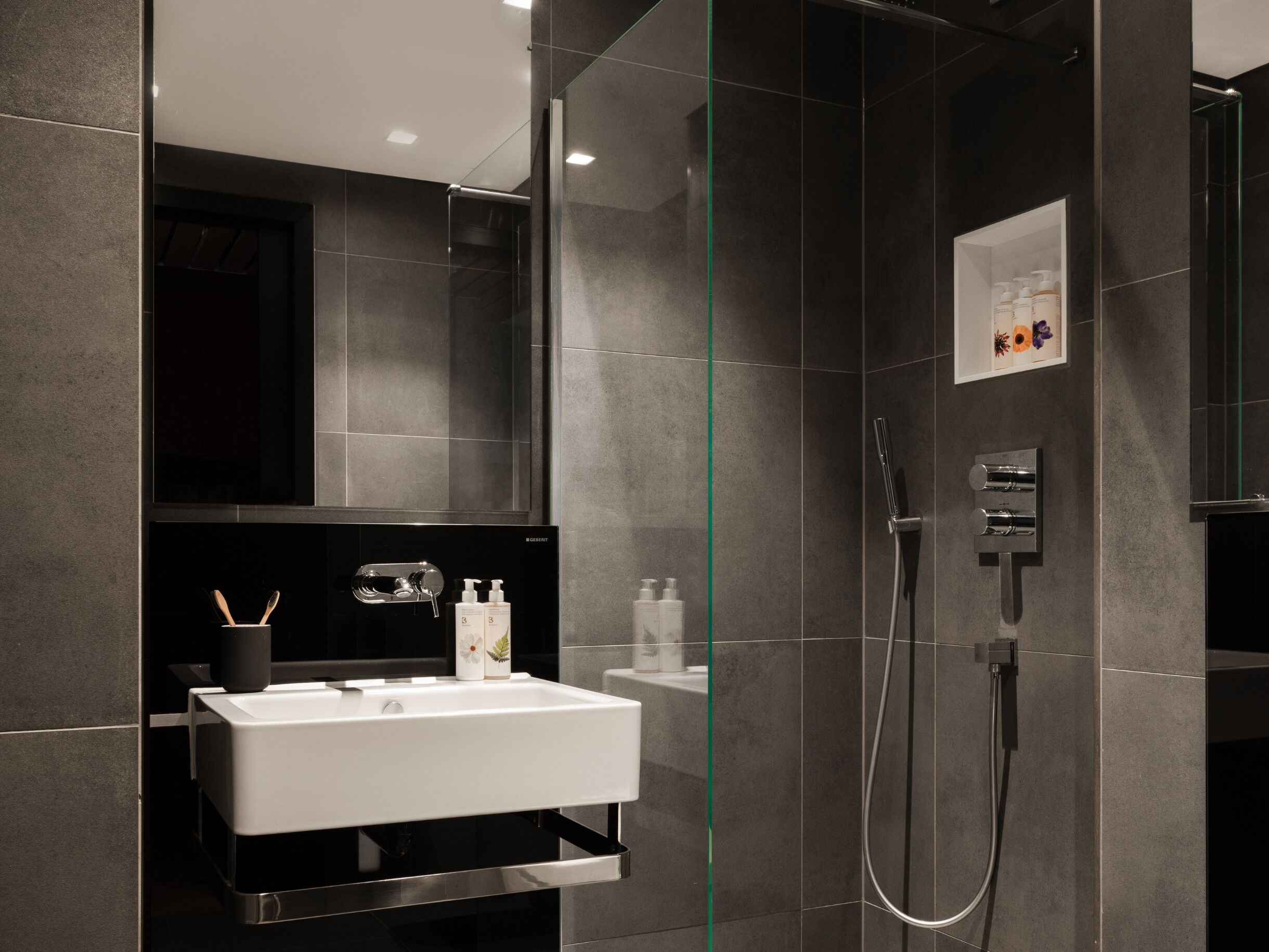 A modern bathroom with a glass-enclosed shower, a white sink, and a mirror above it.