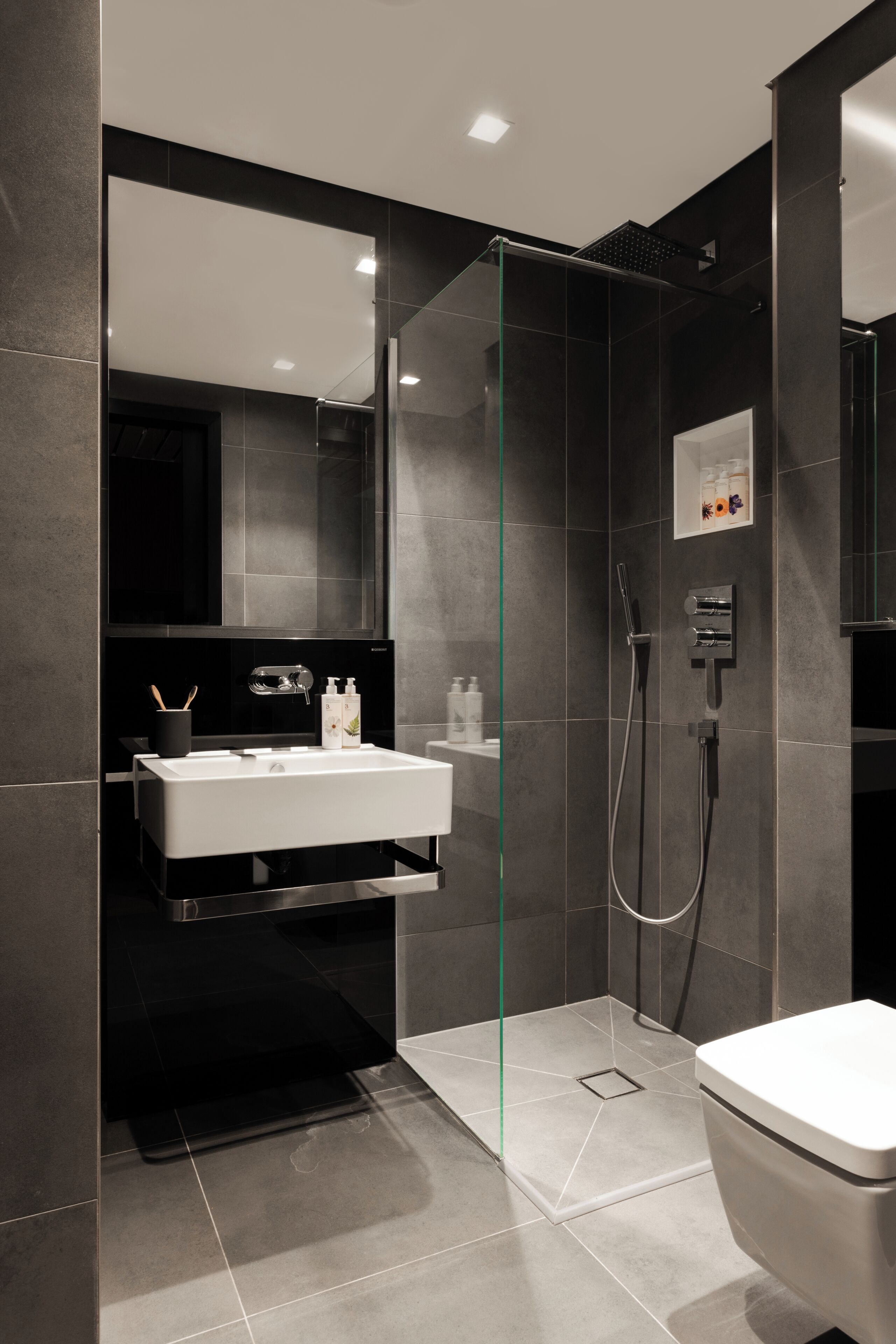 Une salle de bain moderne avec une douche à parois de verre, un lavabo blanc et des toilettes.