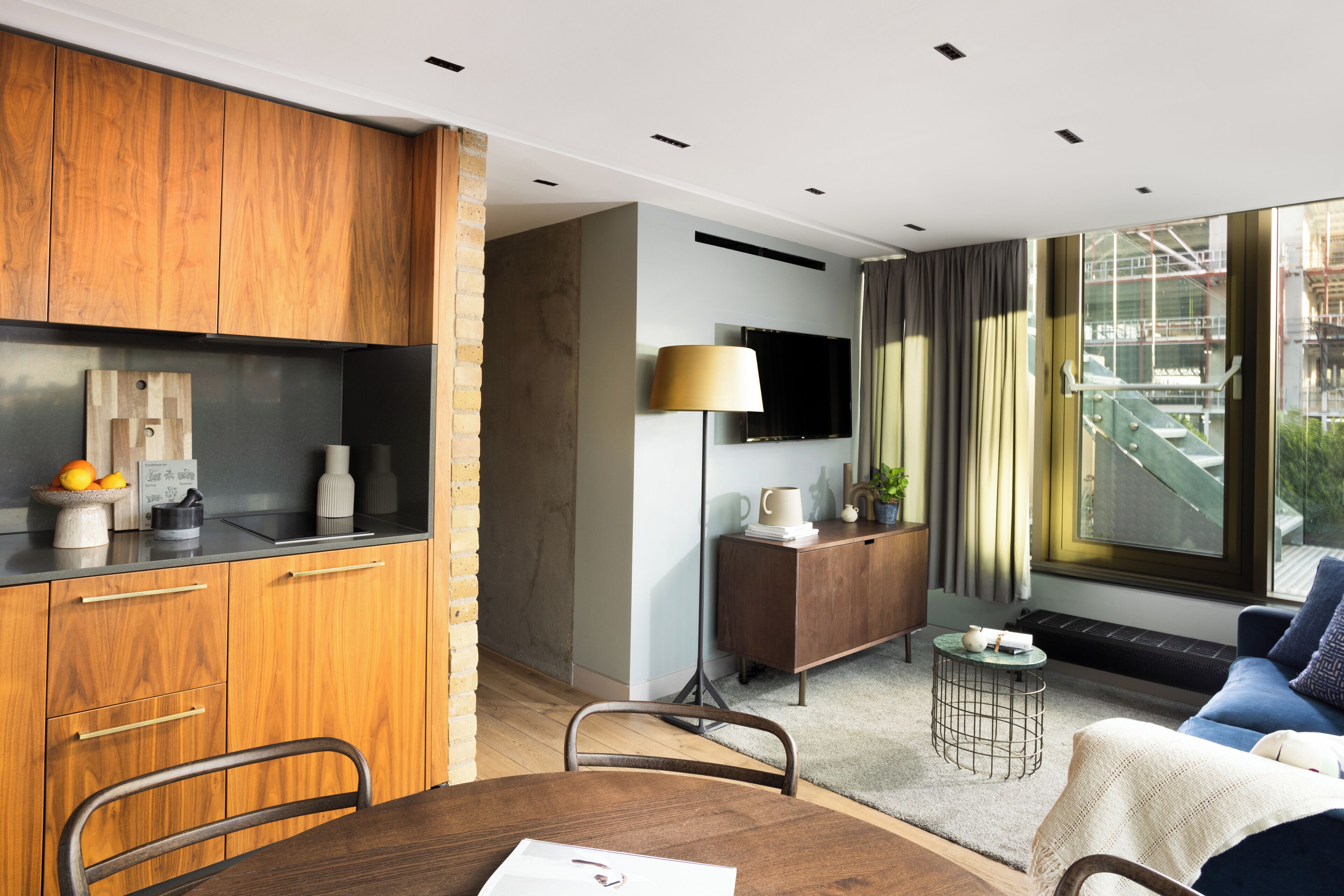 Una cocina moderna con armarios de madera, una mesa de comedor con sillas, un televisor y un ventanal con vistas a la ciudad.