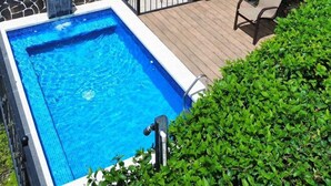 Ein zweistöckiges Haus mit Schwimmbad, einer Treppe und einem Balkon mit Pflanzen.