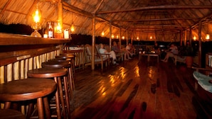 Un bar interior con mobiliario de madera y techo de paja.