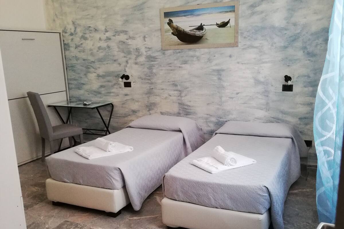 A hotel room with two beds, a desk, and a chair.
