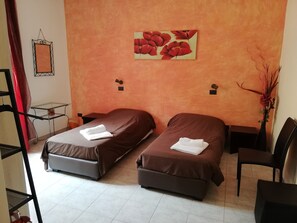A hotel room with two beds, a small table, and a chair. - La Maison di Luca (Verona)