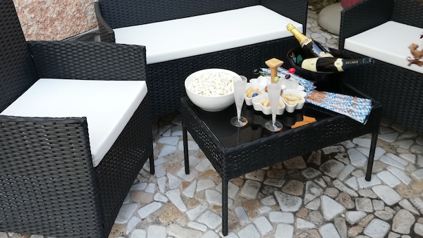 A patio area with wicker furniture, a table with a bowl of snacks, and a small statue. - La Maison di Luca (Verona)