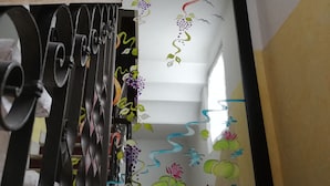 A staircase with a handrail and a wall with colorful floral and abstract designs. - La Maison di Luca (Verona)