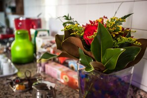 A kitchen counter with a vase of flowers, a green bottle, and various kitchen items. - La Maison di Luca (Verona)