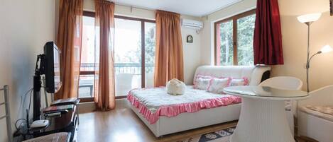 Quarto com cama, escrivaninha, cadeira, luminária e vista para o exterior.