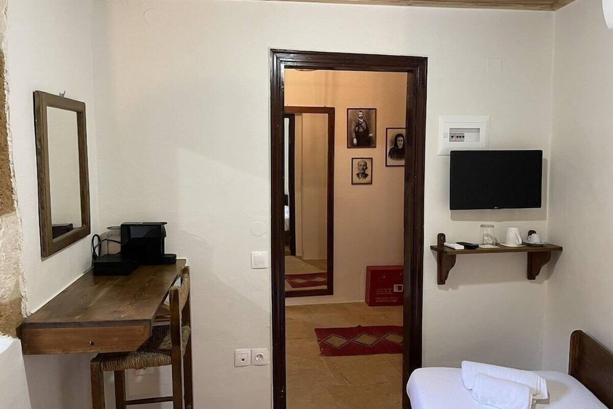 Habitación de hotel con una cama, un escritorio con computadora, un televisor y un estante con objetos.