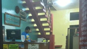 A reception area with a staircase, a counter with a sign, and a patterned floor. - Hotel Posada Tayazal (Flores)