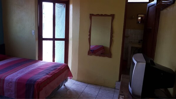 A bedroom with a bed, a mirror, and a television. - Hotel Posada Tayazal (Flores)