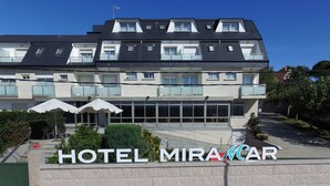 Un hotel de varios pisos con un diseño moderno, que presenta una entrada destacada con un letrero que dice "HOTEL MIRACAR".