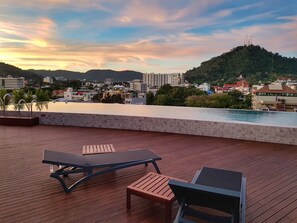 A rooftop terrace with wooden flooring, two lounge chairs, and a pool. - EcoLoft Hotel (Phuket)