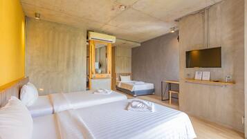 A hotel room with two beds, a wooden desk, a flat-screen TV, and a mirror.