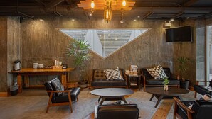 A cozy lounge area with a wooden ceiling, a large window, and a flat-screen TV mounted on the wall. - EcoLoft Hotel (Phuket)