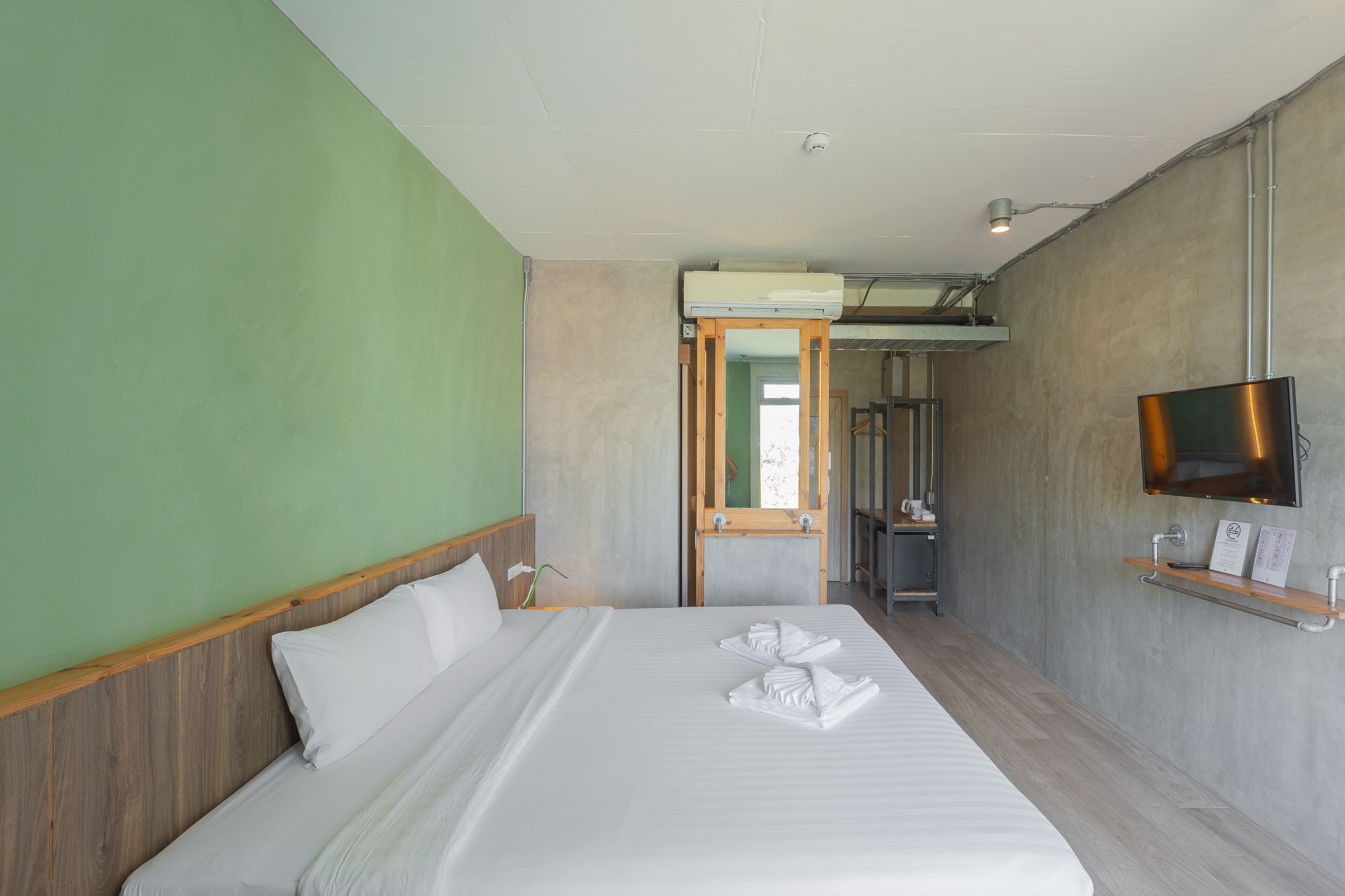 Een hotelkamer met een bed, een aan de muur bevestigde televisie en een houten hoofdeinde.