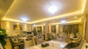 A hotel dining area with multiple tables and chairs, a chandelier, and a painting on the wall. - Vienna Hotel (Sanya Yalong Bay Qianguqing) (Sanya)