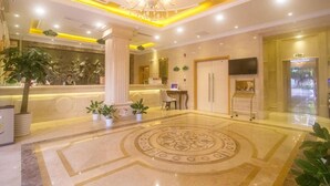 A hotel lobby with a reception desk, a chandelier, a television, and a patterned floor. - Vienna Hotel (Sanya Yalong Bay Qianguqing) (Sanya)