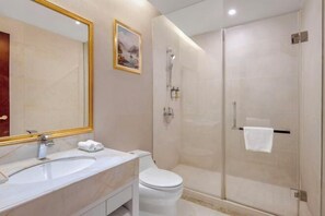 A modern bathroom with a large mirror, a sink, a toilet, and a glass-enclosed shower area.