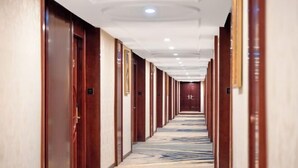 A hotel corridor with wooden doors, a marble-patterned floor, and recessed lighting.