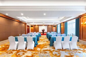 A conference room with rows of tables and chairs, a podium, and a carpeted floor. - Vienna Hotel (Ninghai) (Ninghai)