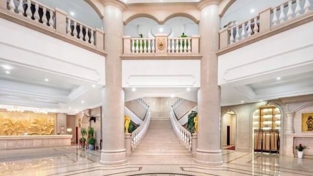 A grand lobby with a marble staircase, high ceilings, and classical architecture.