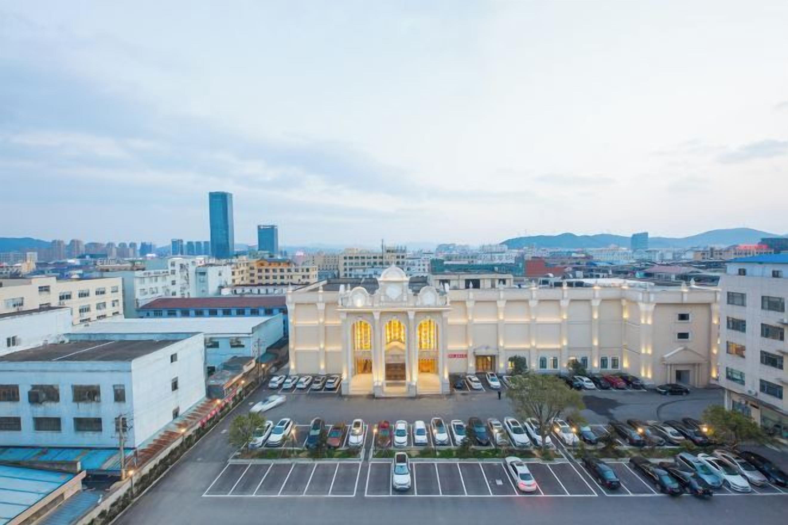 A hotel with a parking lot and a view of the cityscape.