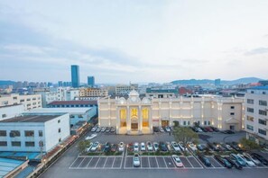 A hotel with a parking lot and a view of the cityscape. - Vienna Hotel (Ninghai) (Ninghai)