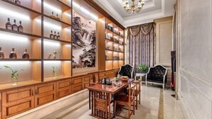 A traditional library with wooden bookshelves, a dining table, and chairs.
