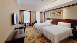 Une chambre d’hôtel avec deux lits, un bureau, une chaise et un téléviseur.