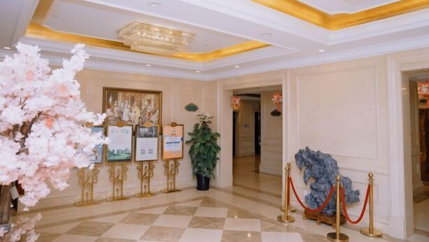 A hotel lobby with a checkered floor, a chandelier, framed pictures on easels, and a red rope barrier. - Vienna Hotel (Shanghai Wild Animal Park Metro Station) (Shanghai)