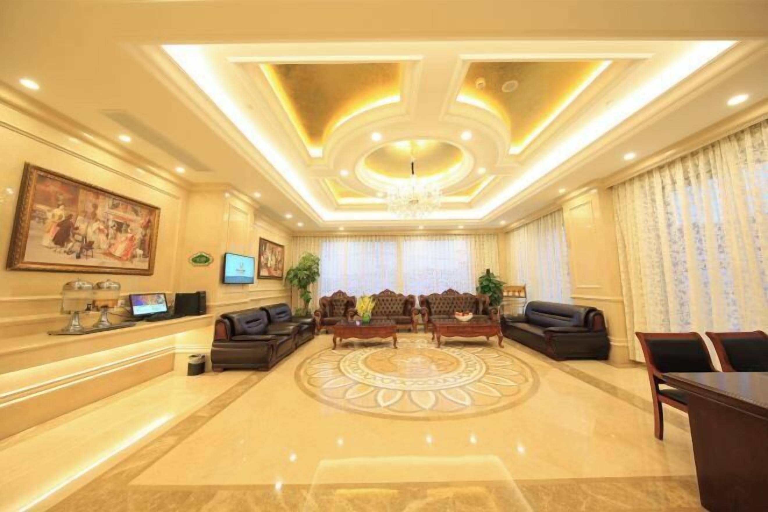 A spacious lobby with a central seating area, a reception desk, and a chandelier.