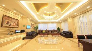 A spacious lobby with a central seating area, a reception desk, and a chandelier.