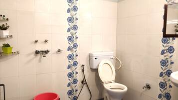 A bathroom with a toilet, shower, and sink.