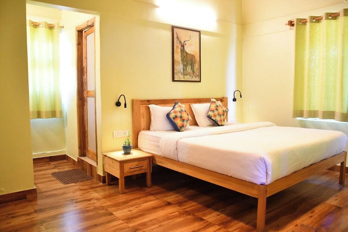 Quarto com cama de madeira, mesa de cabeceira, luminária na parede e pintura de um veado.