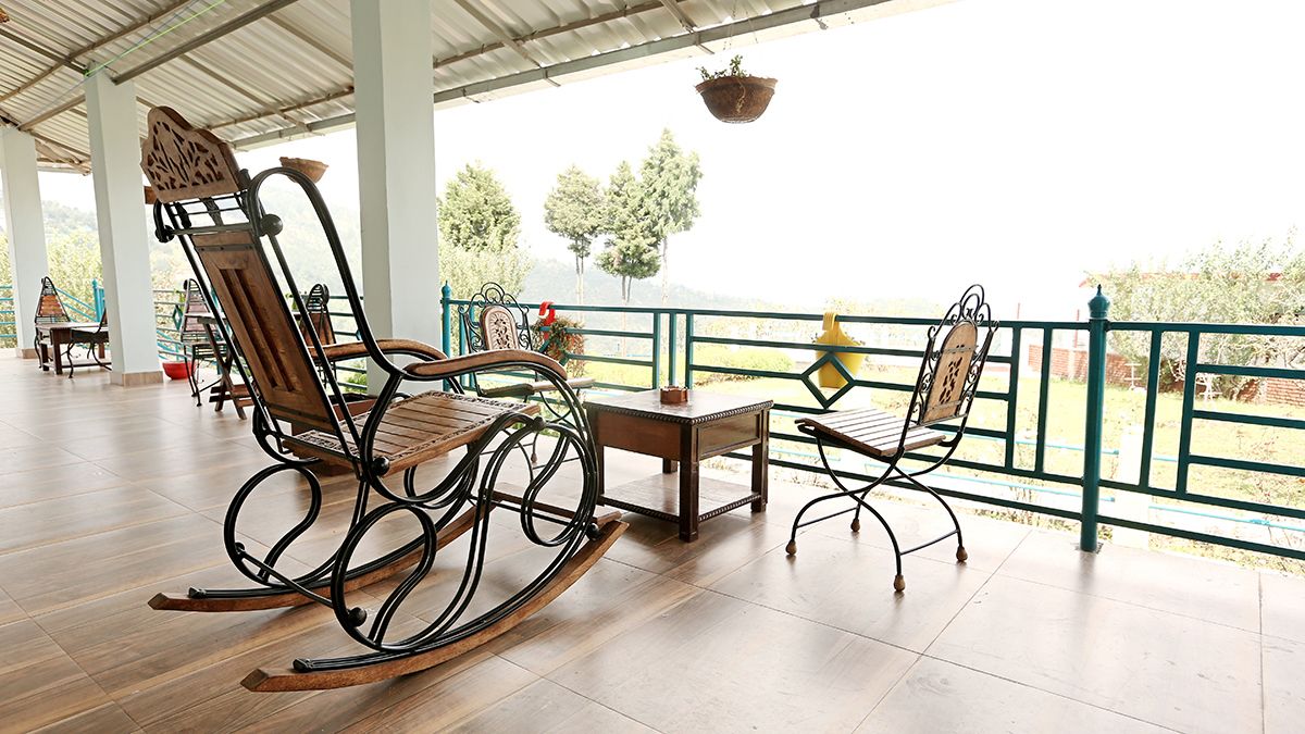 Un espace extérieur aménagé avec des fauteuils à bascule en bois et une table, offrant une vue sur un paysage pittoresque.