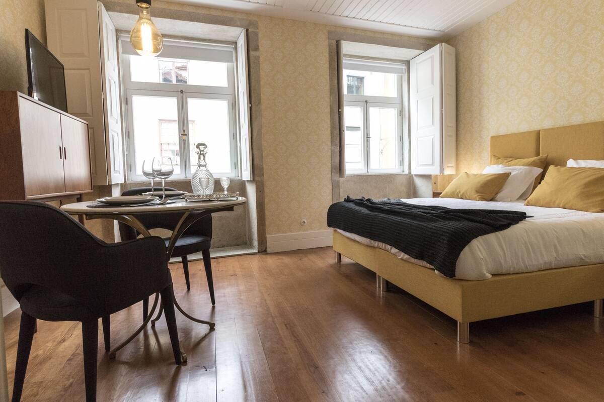 A bedroom with a bed, a desk with a chair, and a window.