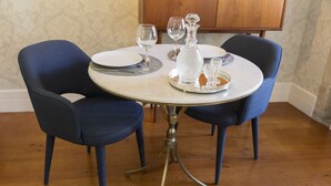 A round dining table with two blue chairs, a crystal decanter, and wine glasses on a tray. - Casa da Picaria (Porto)