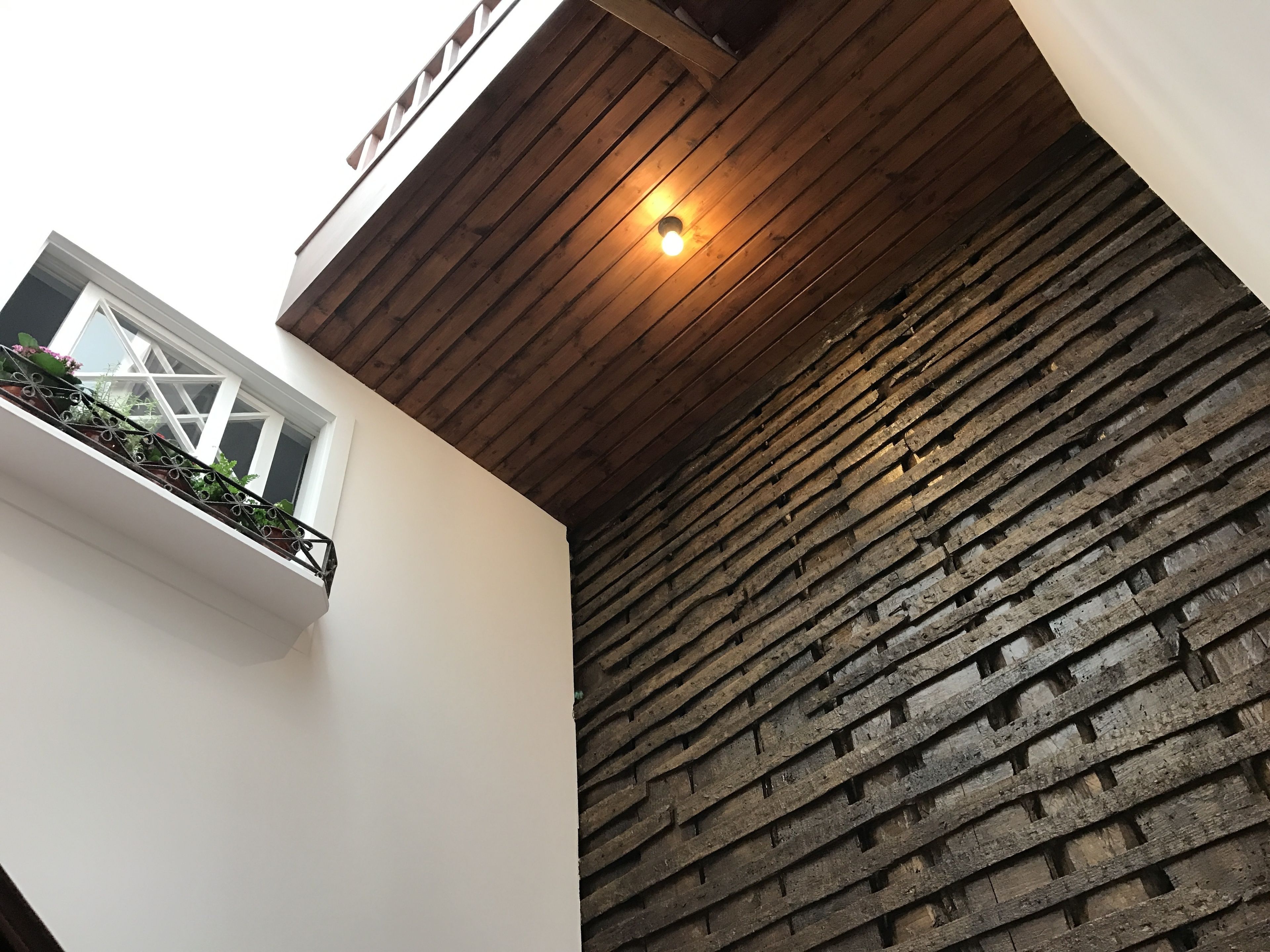 A modern interior with a wooden ceiling, a white wall, and a textured brick wall.