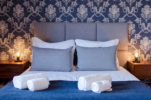 A neatly made bed with grey and white bedding, two white towels, and a blue blanket. - Casa da Picaria (Porto)