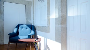 A room with a blue armchair, a wooden coffee table, and a door with a geometric wall decal. - Casa da Picaria (Porto)