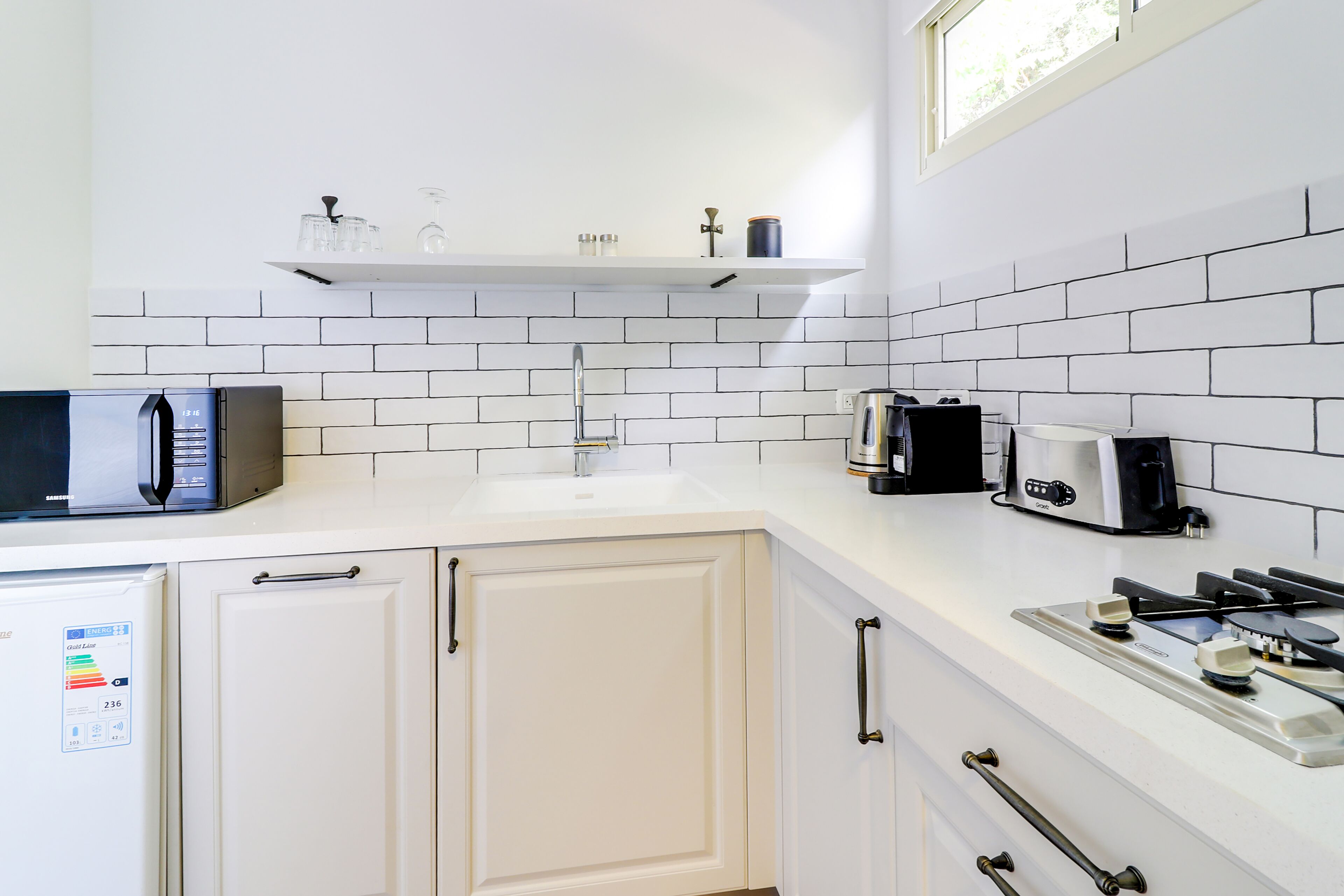 Una cocina moderna con armarios blancos, un microondas, una cafetera y una estufa a gas.