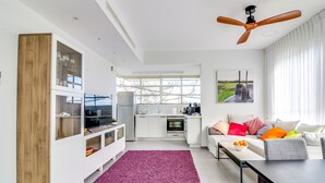 A modern kitchen with white cabinets, a wooden cabinet, and a dining area with a table and chairs. - Carmel Boutique (Haifa)