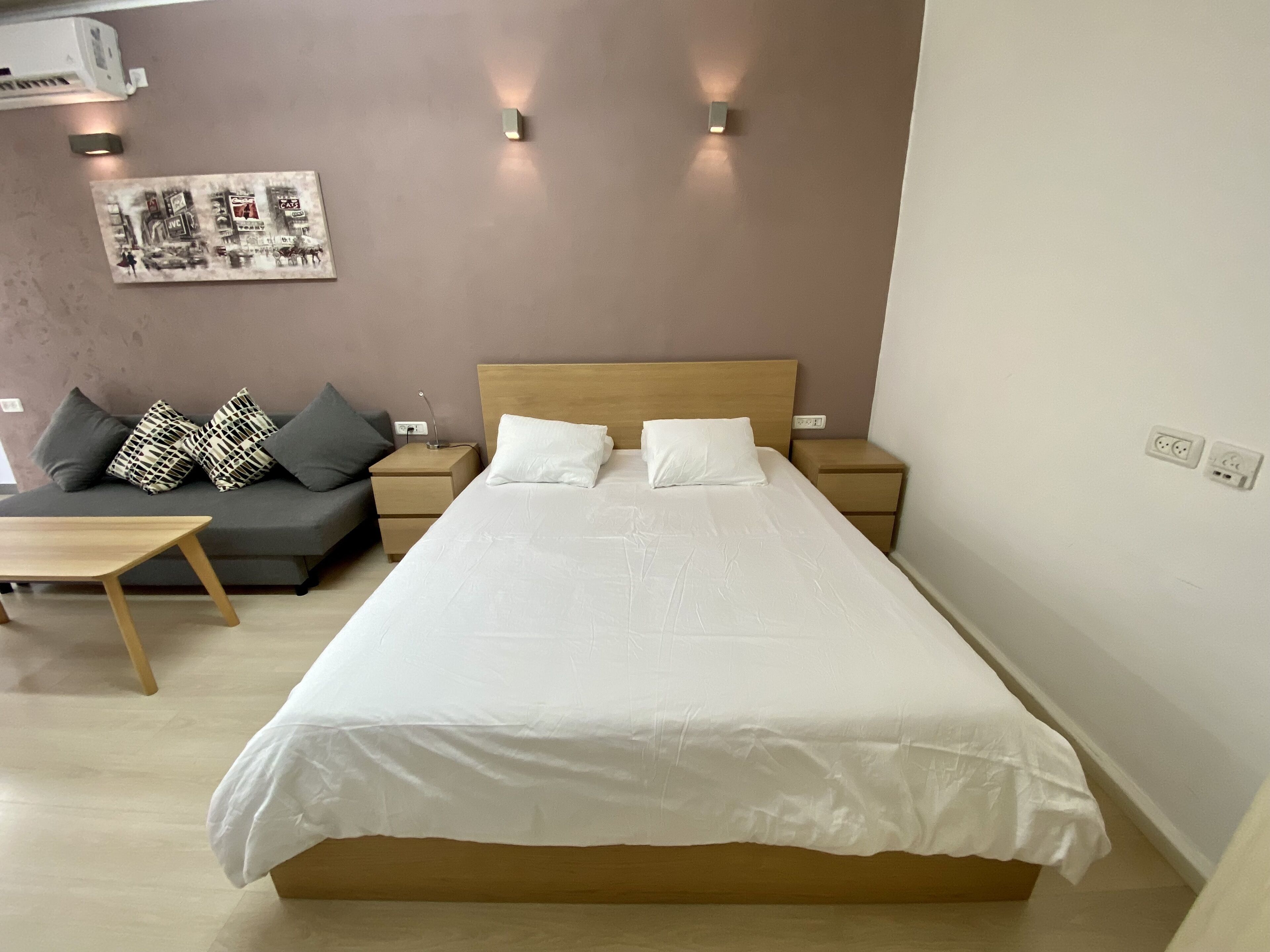 Une chambre à coucher bien rangée, avec un grand lit, une table de chevet, une commode, un canapé et une petite table.