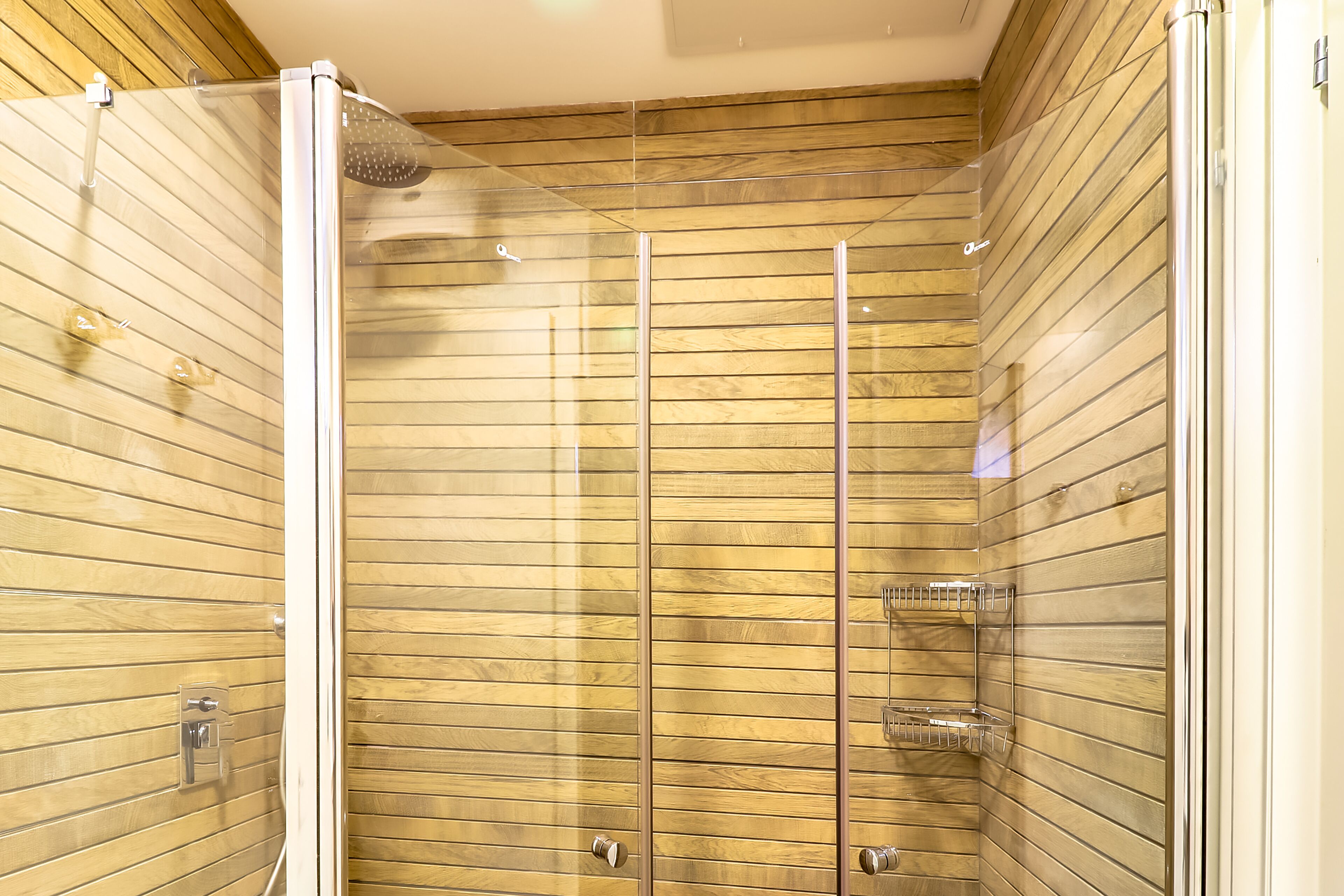 Een douche met een glazen cabine en houten lambrisering.