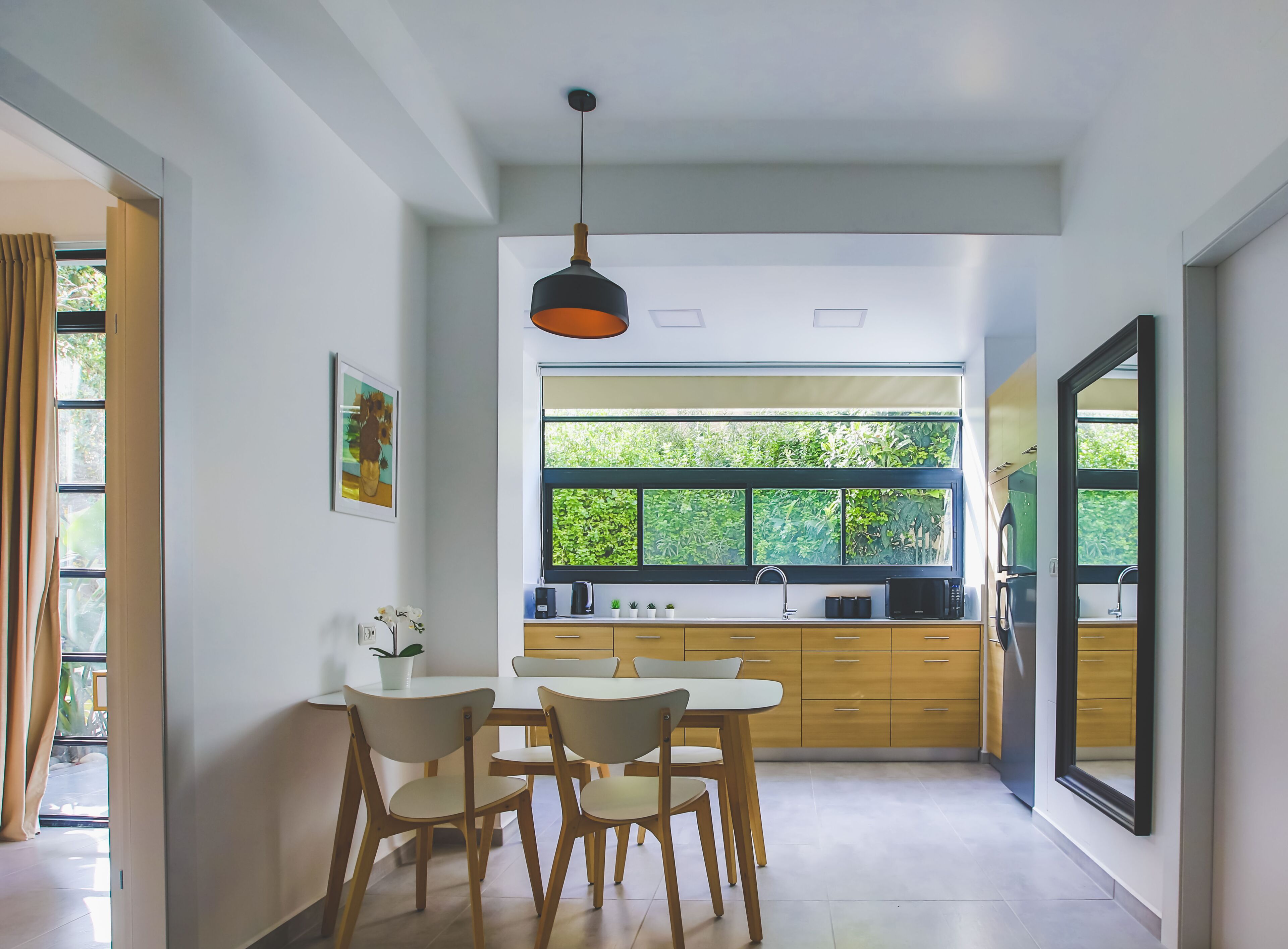 Une cuisine moderne dotée d’une grande fenêtre, de meubles en bois et d’un coin repas avec une table et des chaises.